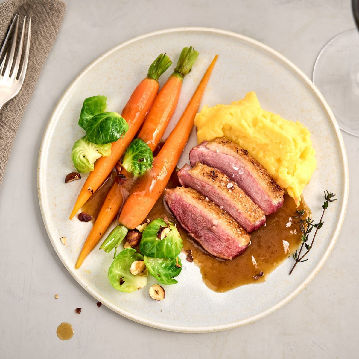 Festliche rosa gebratene Entenbrust mit Karotten, Rosenkohl, Kartoffelpüree und Haselnüssen