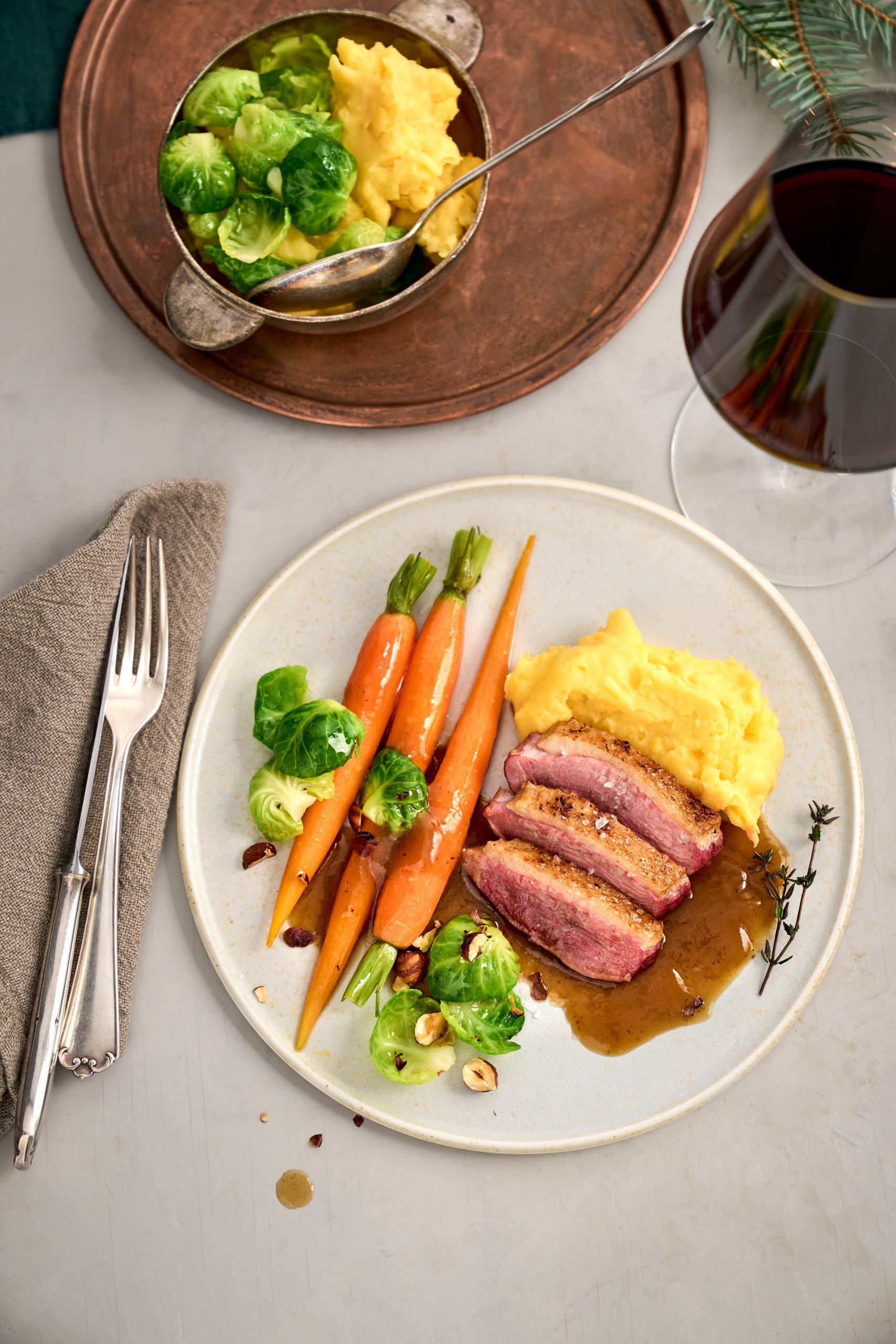 Festliche rosa gebratene Entenbrust mit Karotten, Rosenkohl, Kartoffelpüree und Haselnüssen